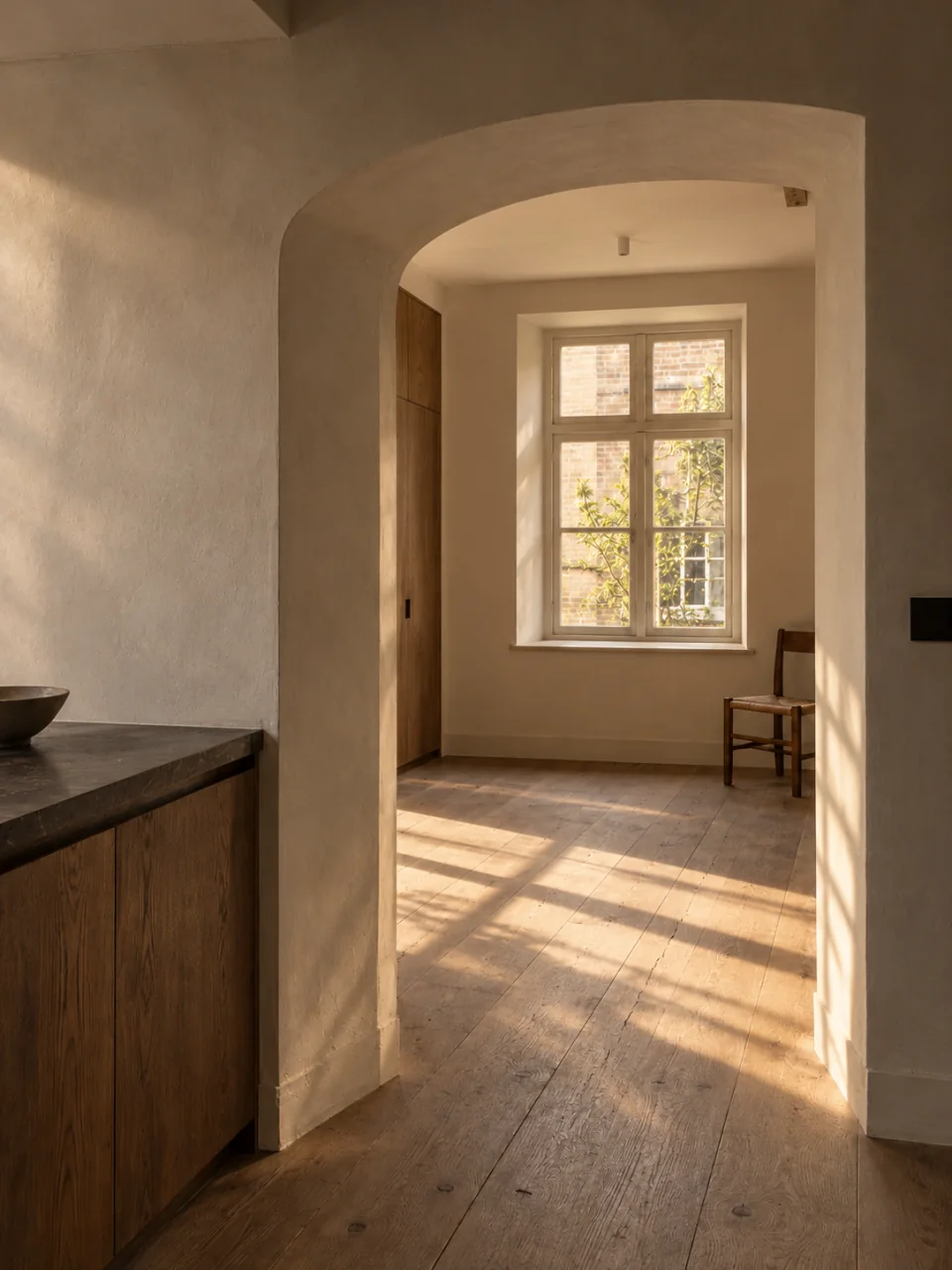 Een gerenoveerd interieur met een gepleisterde doorgang en houten vloer